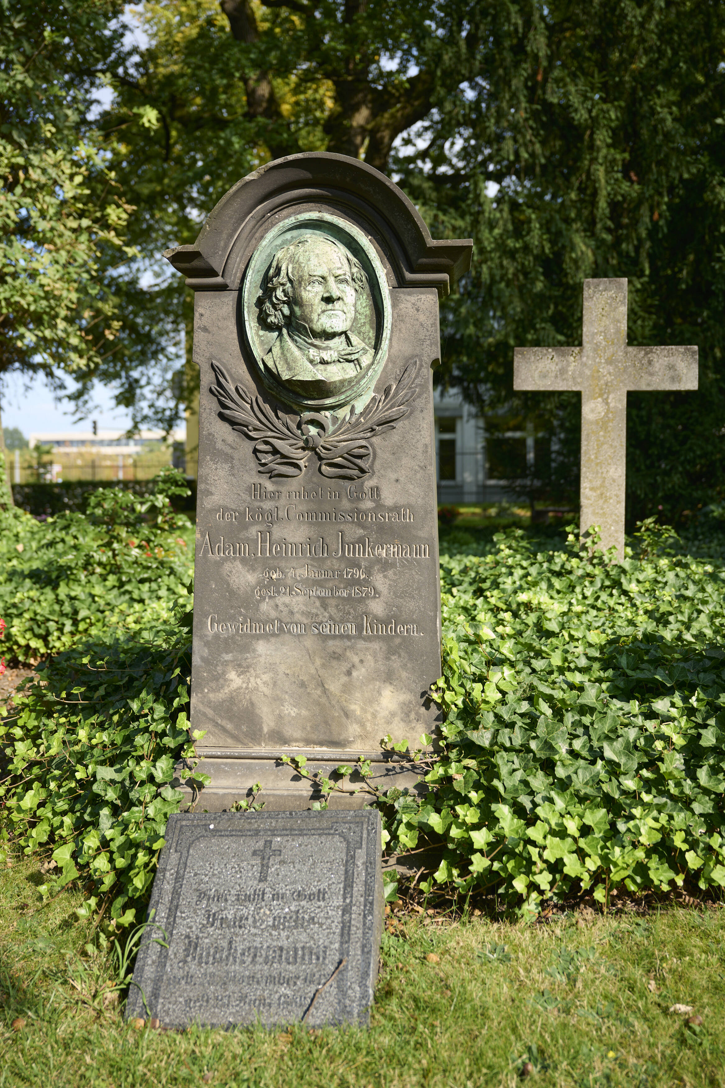 Bildtitel - Grabstätte von Adam Heinrich Junkermann: Ein Grabstein mit einem Porträt des Verstorbenen als herausgehobenes Bronzerelief.